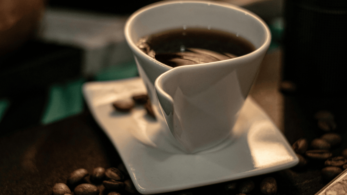 coffee cup sitting on a counter with coffee beans nearby